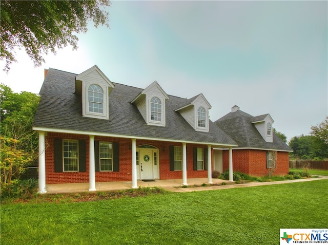 cape cod home with a front lawn and covered porch