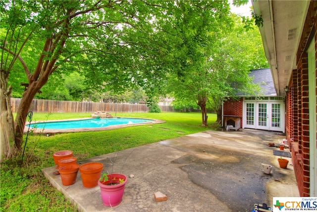 view of yard featuring a fenced in pool, a patio, and french doors