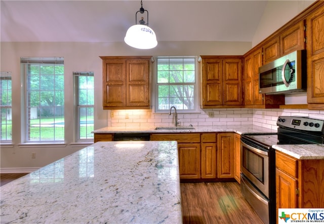 kitchen with a wealth of natural light, appliances with stainless steel finishes, hanging light fixtures, and sink