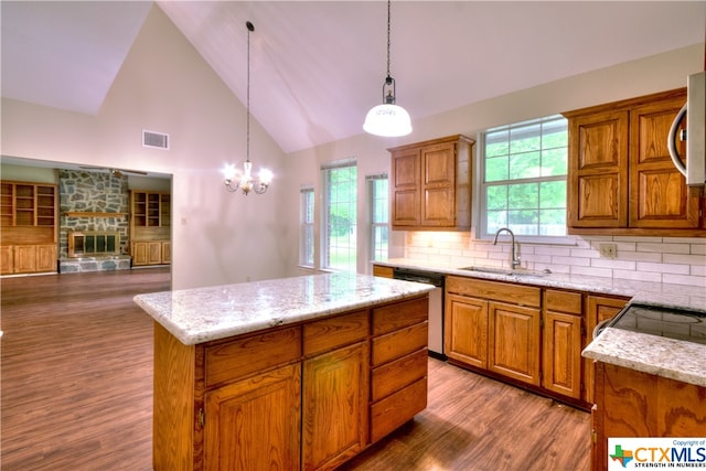 kitchen with stainless steel appliances, sink, high vaulted ceiling, a kitchen island, and pendant lighting