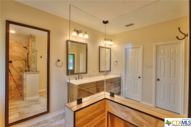 bathroom featuring tiled shower and vanity