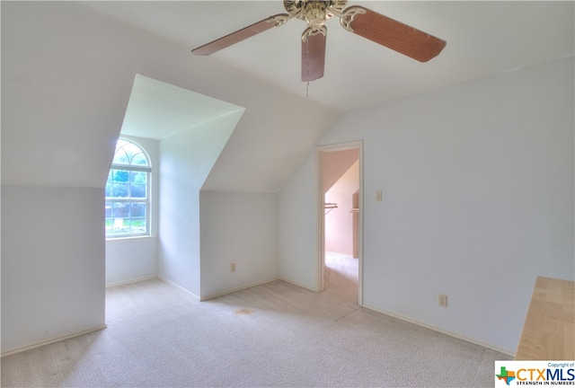 additional living space with vaulted ceiling, light colored carpet, and ceiling fan