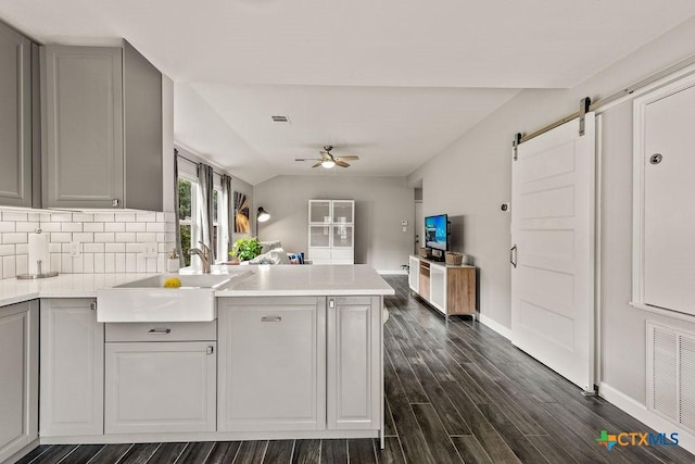 2075 Sungate Dr, New Braunfels, TX 78130 - kitchen featuring gray cabinetry, a ceiling fan, a barn door, tasteful backsplash, and dark wood finished floors