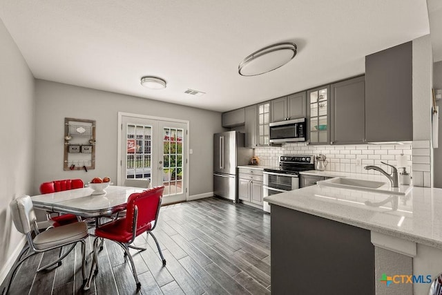 2075 Sungate Dr, New Braunfels, TX 78130 - kitchen with appliances with stainless steel finishes, gray cabinets, french doors, glass insert cabinets, and light stone counters