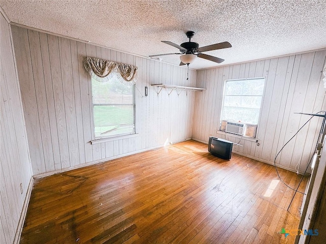 1606 Milam Dr, Victoria, TX 77901 - spare room featuring hardwood / wood-style flooring, a ceiling fan, a textured ceiling, cooling unit, and wood walls