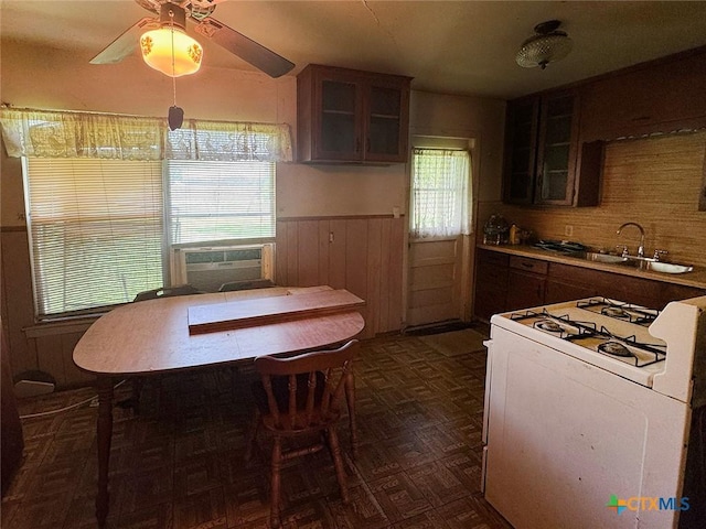 1606 Milam Dr, Victoria, TX 77901 - kitchen with white gas stove, wainscoting, glass insert cabinets, a ceiling fan, and cooling unit