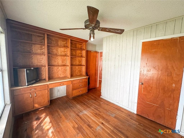 1606 Milam Dr, Victoria, TX 77901 - unfurnished office with wood-type flooring, wood walls, built in desk, a ceiling fan, and a textured ceiling