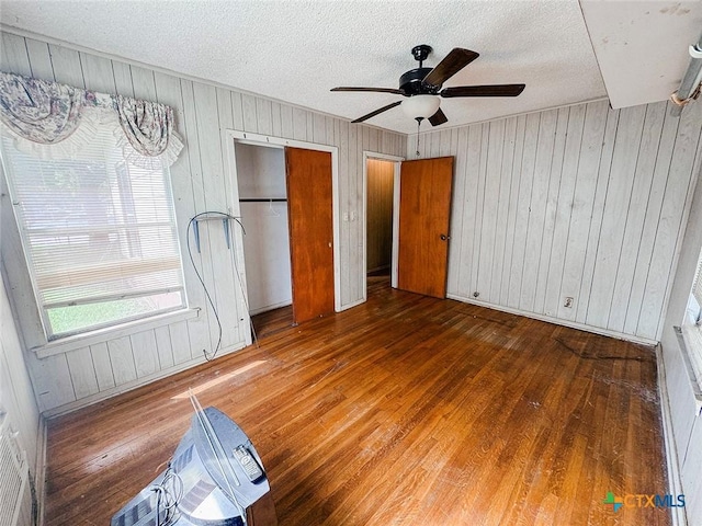 1606 Milam Dr, Victoria, TX 77901 - unfurnished bedroom with hardwood / wood-style floors, wooden walls, a textured ceiling, ceiling fan, and a closet