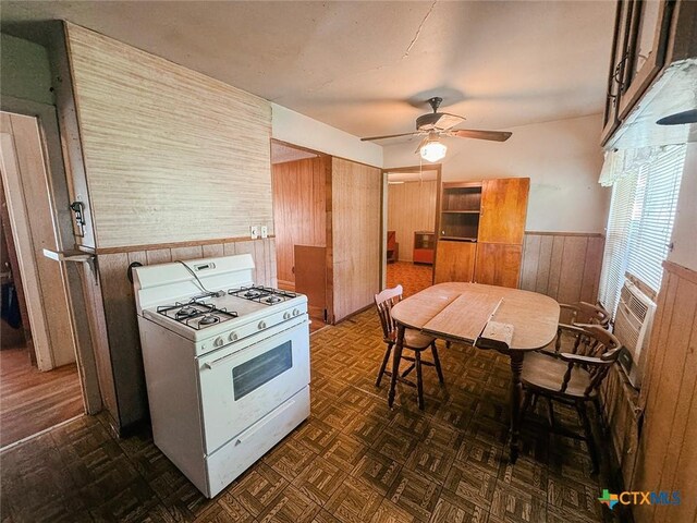 1606 Milam Dr, Victoria, TX 77901 - kitchen with white gas range, wooden walls, wainscoting, a ceiling fan, and cooling unit