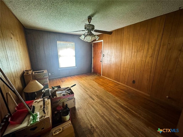 1606 Milam Dr, Victoria, TX 77901 - unfurnished bedroom with wood finished floors, wooden walls, ceiling fan, and a textured ceiling