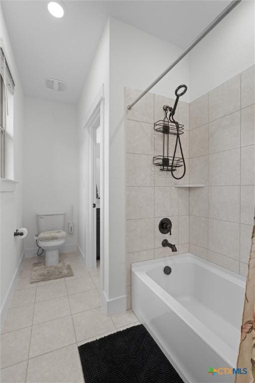 bathroom with tiled shower / bath combo, tile patterned flooring, and toilet