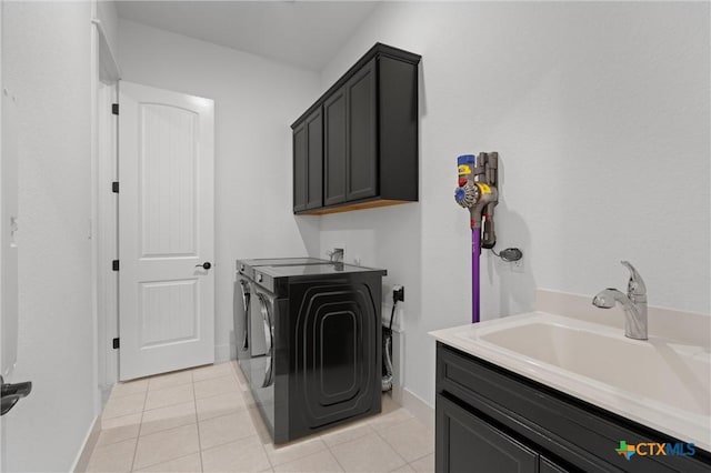 clothes washing area with sink, cabinets, washer and dryer, and light tile patterned floors