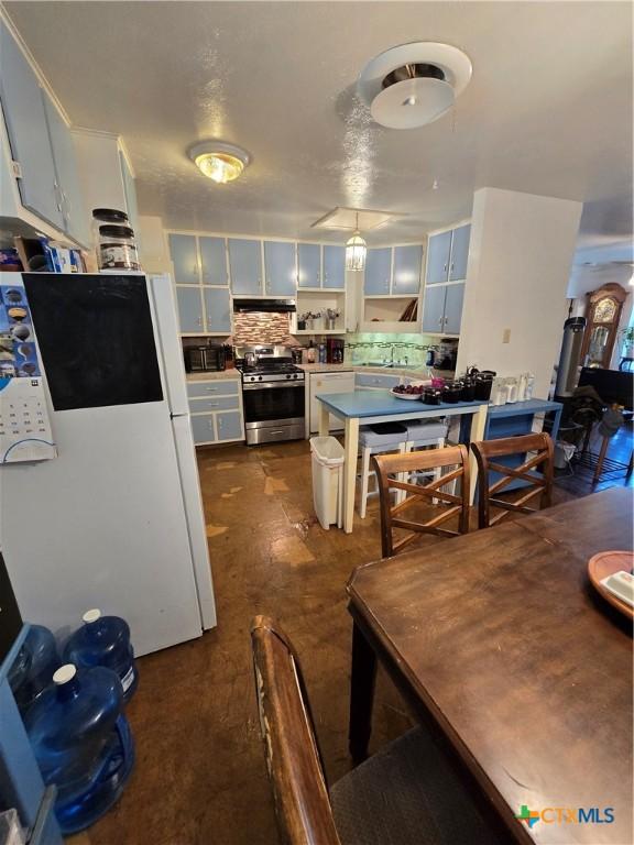 612 S 1st St, Copperas Cove, TX 76522 - kitchen with stainless steel range with gas stovetop, freestanding refrigerator, tasteful backsplash, under cabinet range hood, and a peninsula
