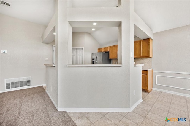 816 Woodhollow Dr, Temple, TX 76502 - kitchen with stainless steel fridge, lofted ceiling, brown cabinetry, light tile patterned floors, and recessed lighting