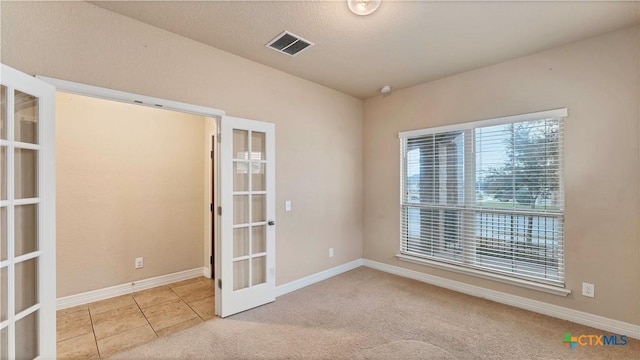 spare room featuring french doors and light tile patterned floors