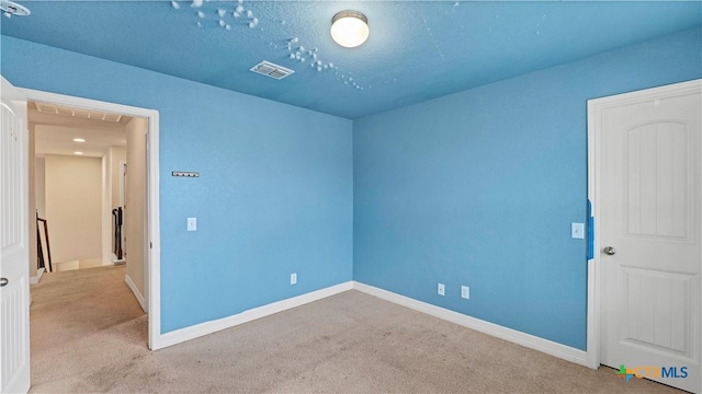 carpeted empty room featuring a textured ceiling