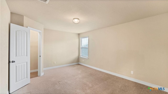 empty room with light carpet and a textured ceiling