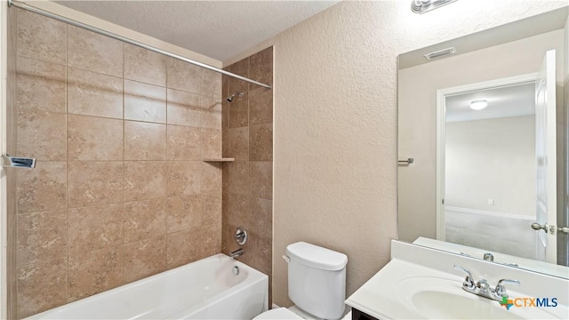 full bathroom with a textured ceiling, vanity, toilet, and tiled shower / bath