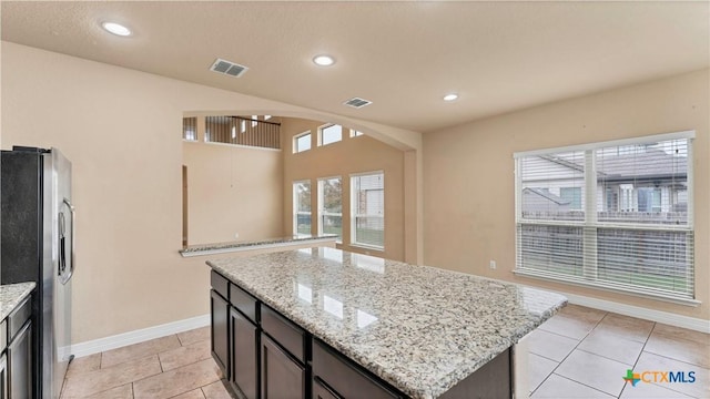 kitchen featuring a center island, stainless steel fridge, and light stone countertops