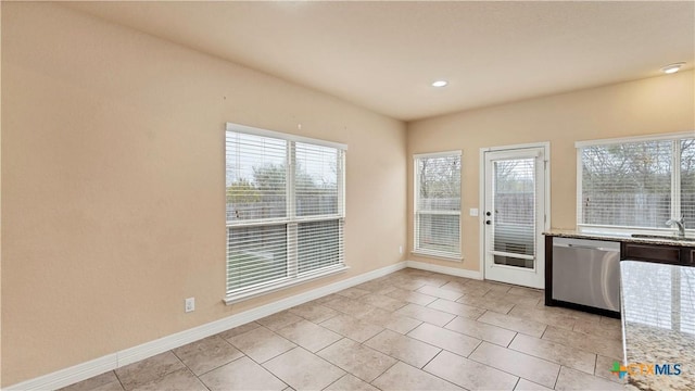 interior space featuring dishwasher, light stone counters, light tile patterned flooring, and sink