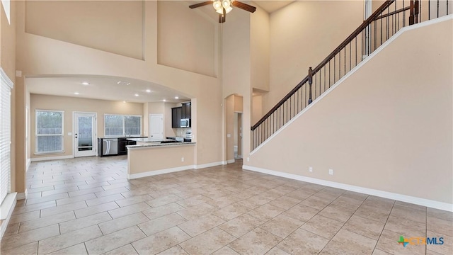 unfurnished living room featuring tile patterned floors, ceiling fan, and a high ceiling