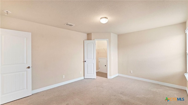 spare room with a textured ceiling and light colored carpet