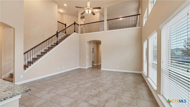 unfurnished living room featuring a towering ceiling and ceiling fan