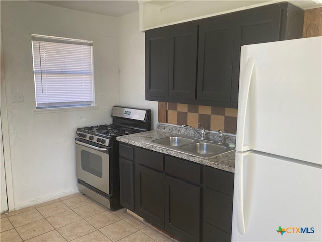 kitchen with light tile patterned floors, stainless steel gas range, white fridge, and sink