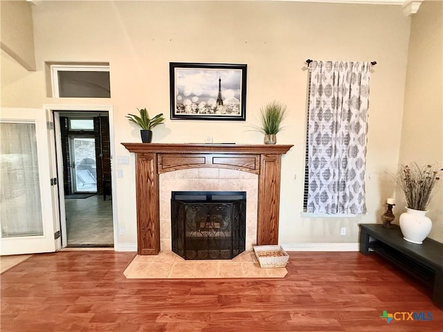 unfurnished room with wood-type flooring and a tile fireplace