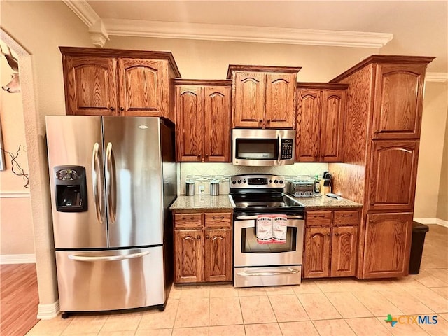 kitchen featuring light tile patterned flooring, decorative backsplash, ornamental molding, stainless steel appliances, and light stone countertops