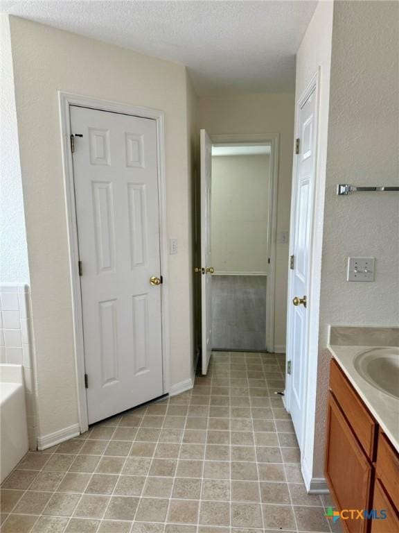 bathroom with a bath, vanity, baseboards, and tile patterned floors