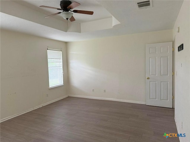 unfurnished room with wood finished floors, baseboards, a ceiling fan, and visible vents
