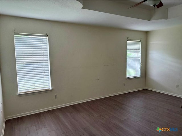 spare room featuring a wealth of natural light, baseboards, a ceiling fan, and wood finished floors
