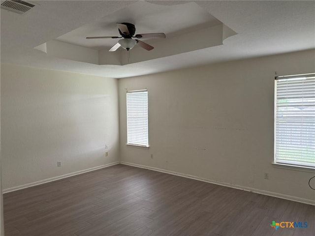 unfurnished room featuring plenty of natural light, visible vents, ceiling fan, and dark wood finished floors