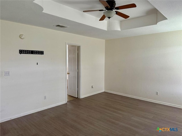 spare room with visible vents, baseboards, a raised ceiling, ceiling fan, and wood finished floors