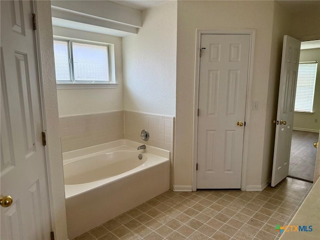 full bathroom featuring tile patterned floors, baseboards, and a garden tub