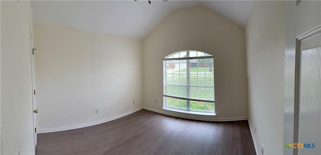 spare room featuring dark wood-style flooring, baseboards, and vaulted ceiling
