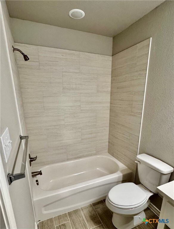 full bathroom with vanity, tiled shower / bath combo, and toilet