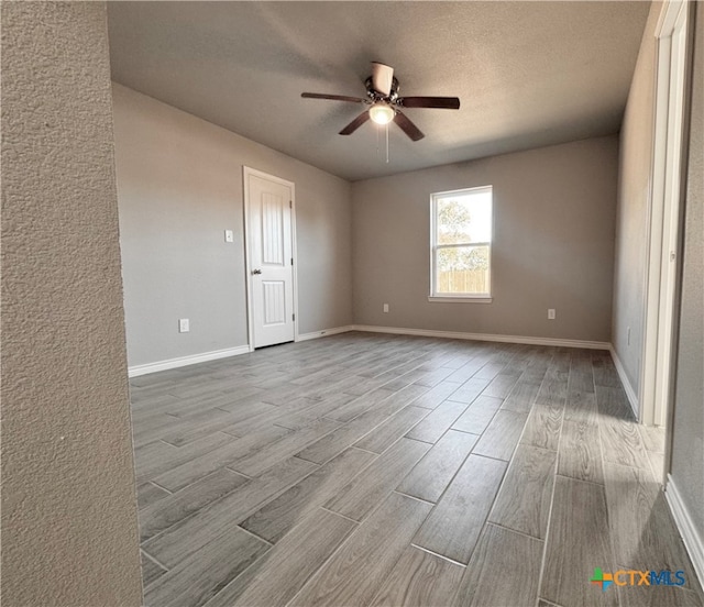 spare room with ceiling fan, a textured ceiling, and light wood-type flooring