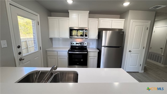 kitchen with white cabinetry, sink, wood-type flooring, and appliances with stainless steel finishes