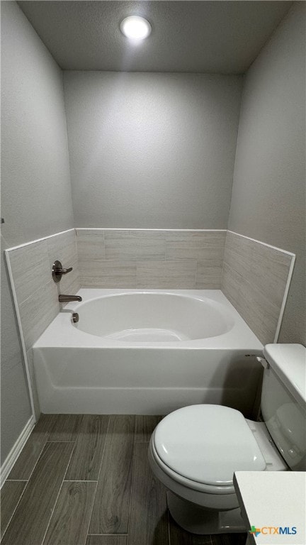 bathroom featuring hardwood / wood-style flooring, a bathtub, toilet, and a textured ceiling