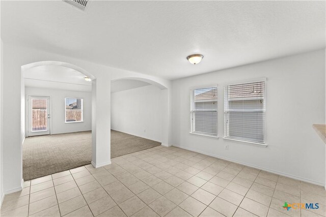 1032 Sandwell Ct, Seguin, TX 78155 - unfurnished room with light carpet, light tile patterned floors, baseboards, visible vents, and arched walkways
