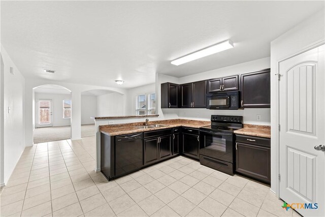 1032 Sandwell Ct, Seguin, TX 78155 - kitchen with light tile patterned flooring, a sink, visible vents, black appliances, and arched walkways
