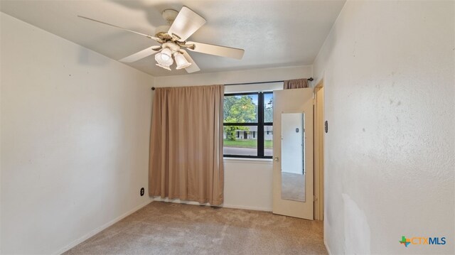 carpeted empty room featuring ceiling fan and baseboards