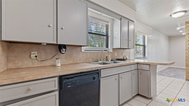 kitchen with a sink, a healthy amount of sunlight, light tile patterned floors, and dishwasher