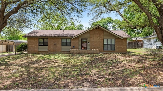 view of front facade featuring brick siding, fence, and a detached carport