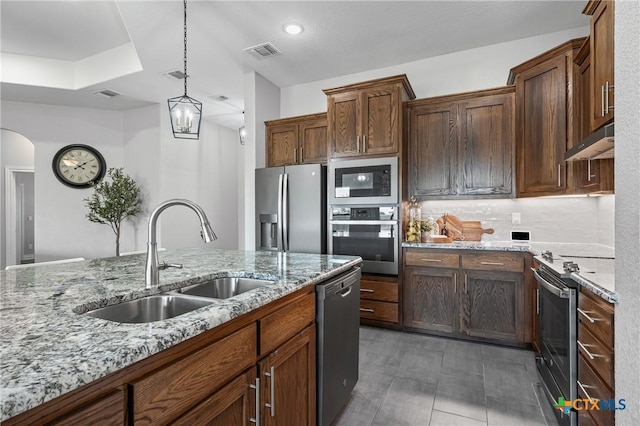3631 Morgan Mill Rd, Kempner, TX 76539 - kitchen with stainless steel appliances, under cabinet range hood, pendant lighting, arched walkways, and light stone countertops