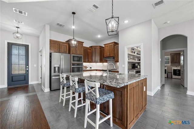 3631 Morgan Mill Rd, Kempner, TX 76539 - kitchen featuring stainless steel appliances, arched walkways, light stone countertops, a breakfast bar area, and an island with sink