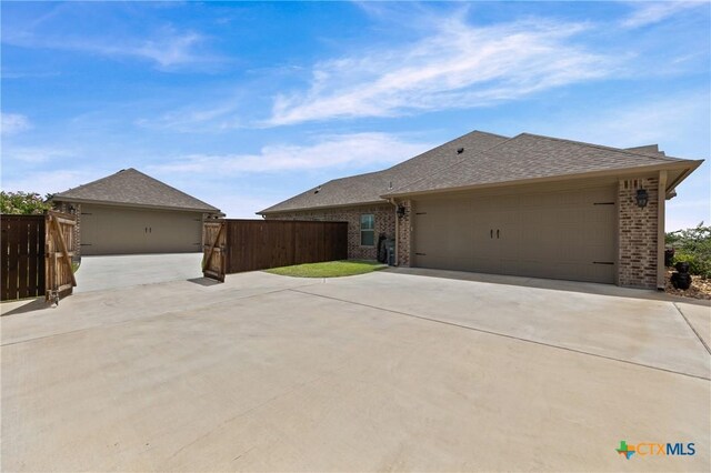 3631 Morgan Mill Rd, Kempner, TX 76539 - view of home's exterior with brick siding, a shingled roof, concrete driveway, an attached garage, and a gate
