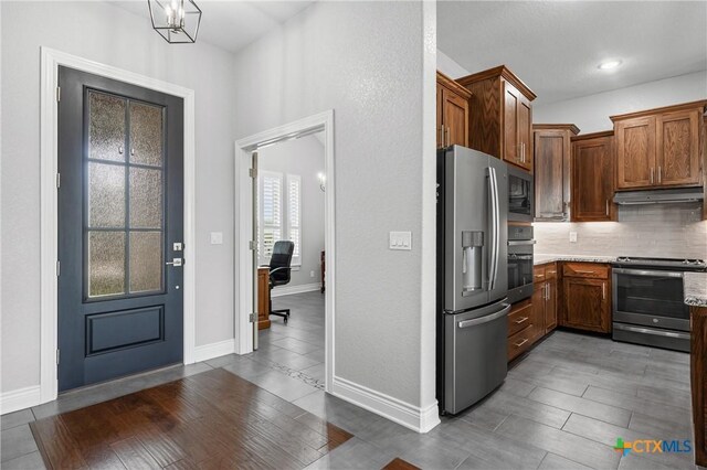 3631 Morgan Mill Rd, Kempner, TX 76539 - kitchen with stainless steel appliances, under cabinet range hood, backsplash, light stone countertops, and brown cabinetry